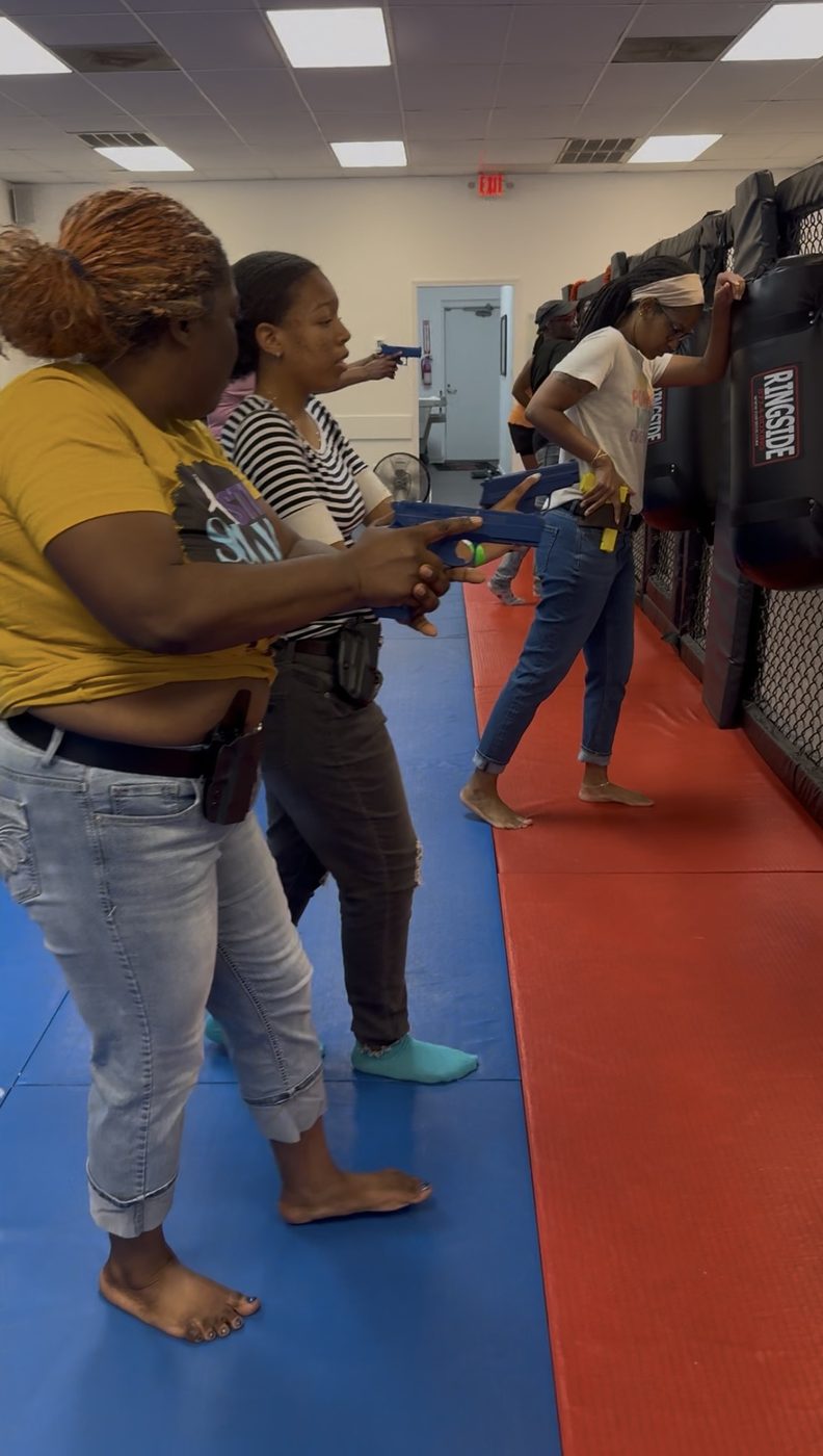 Women practicing gun retention drills together, focused